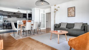 Un salon moderne avec un canapé gris, une table basse et un coin repas comprenant des chaises et une table.