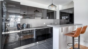 Une cuisine moderne avec des meubles noirs, un plan de travail gris et un luminaire suspendu.