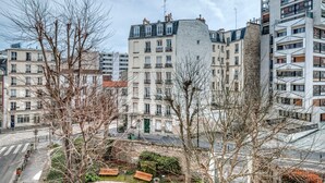 Un immeuble résidentiel à plusieurs étages, dont l’architecture combine des éléments modernes et traditionnels, et qui est doté de balcons et d’une cour intérieure.