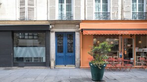 A street view with a blue door, a potted plant, and outdoor seating. - Blueground | Montorgueil/Sentier, nr dining (Paris)