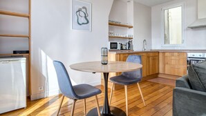 A modern kitchen with wooden cabinets, a round dining table, and two chairs. - Blueground | Montorgueil/Sentier, nr dining (Paris)