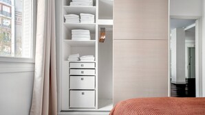 A bedroom with a bed, a wardrobe with folded clothes, and a view of the outside. - Blueground | Arc de Triomphe, nr shopping (Paris)