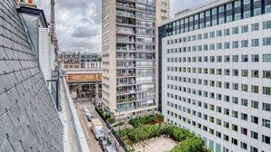 Un immeuble moderne de grande hauteur, doté de nombreux étages, de grandes fenêtres et d’une cour intérieure agrémentée de verdure.