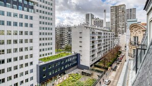 Un immeuble moderne de grande hauteur, doté d’un jardin sur le toit et d’une cour avec des espaces aménagés pour s’asseoir.