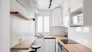Une cuisine de taille réduite avec des meubles blancs, un four à micro-ondes, un lave-vaisselle et un plan de travail en bois.