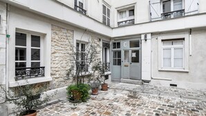 A courtyard with stone flooring, a door labeled 'C', and potted plants.