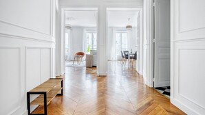 Un hall d’entrée spacieux, doté d’un plancher en bois, de murs blancs et d’un banc.