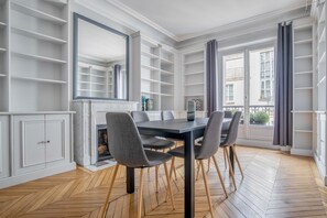 Enjoy meals in this dining room with a large table and six chairs, surrounded by a herringbone-patterned floor and white cabinetry.