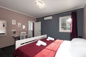 Relax in a serene space with a comfortable bed, bedside table, and desk, offering a peaceful view of the outside.