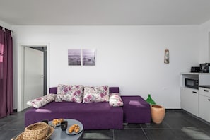 A modern living room with a purple sofa, a dining table with pastries, and a kitchen area with a microwave. - Peaceful Istria - App Pius 1, Labin, Croatia (Labin)