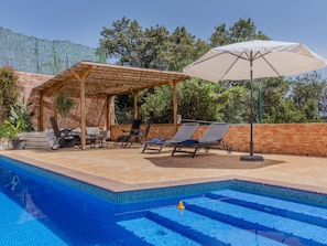 A swimming pool with lounge chairs and a pergola.