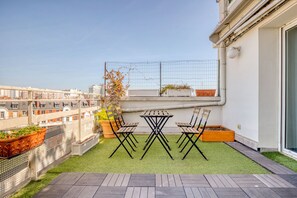 Enjoy a peaceful retreat on the rooftop with a seating area, artificial grass, and a window offering a view of the surrounding buildings.