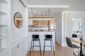Modern kitchen with light cabinetry, central island, and stainless steel appliances.