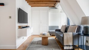 Ein modernes Wohnzimmer mit Flachbildfernseher, einer Couch, einem Couchtisch und einer Lampe.