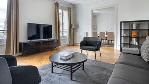 Un soggiorno moderno con una TV a schermo piatto, un divano, un tavolino da caffè e una libreria.