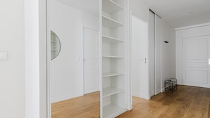 A hallway with a wooden floor, white walls, and a white door with a black handle. - Blueground | Sentier-Montorgueil, foodie area (Paris)