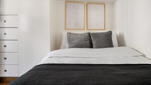 A bedroom with a bed, two pillows, a wardrobe, and two framed pictures on the wall. - Blueground | Europe, nr Gare Saint Lazare (Paris)