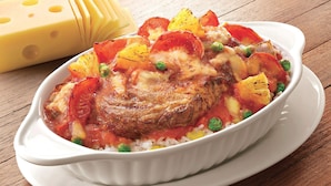 A dish with rice, peas, tomatoes, and a piece of meat in a white dish. - New World Guest House (Kowloon)