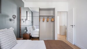 A modern bedroom with a bed, bedside table, and a walk-in closet with hanging space.