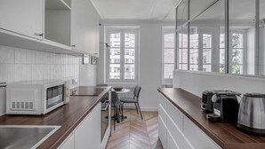 A modern kitchen with white cabinetry, a wooden countertop, a microwave, a coffee maker, and a kettle.