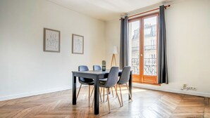Un comedor con una mesa y sillas, una lámpara y dos cuadros en la pared.