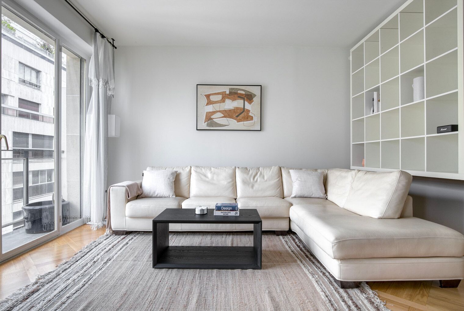 Un salon moderne avec un canapé blanc, une table basse noire et une grande fenêtre.