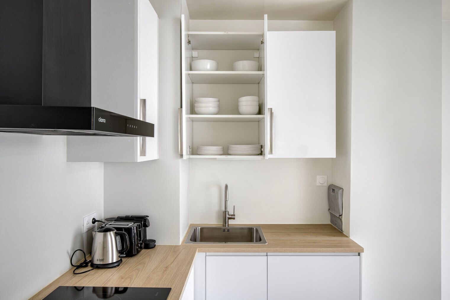 A compact kitchen with white cabinets, a stainless steel sink, and a coffee maker.