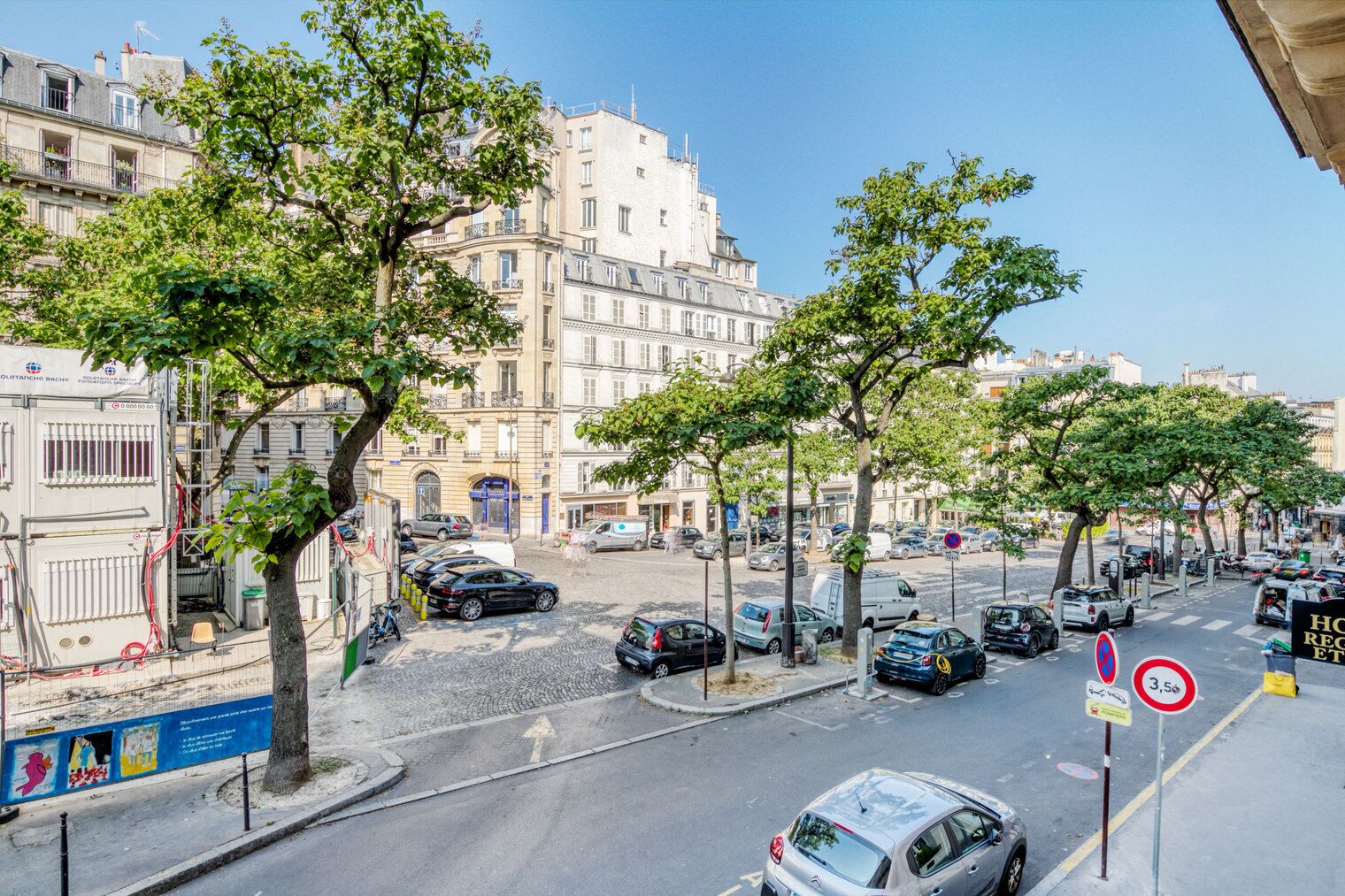 Une vue de rue avec des voitures garées, des arbres et des bâtiments.