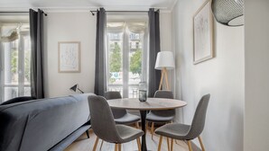 Une pièce moderne avec une table ronde, quatre chaises, un canapé et une lampe.
