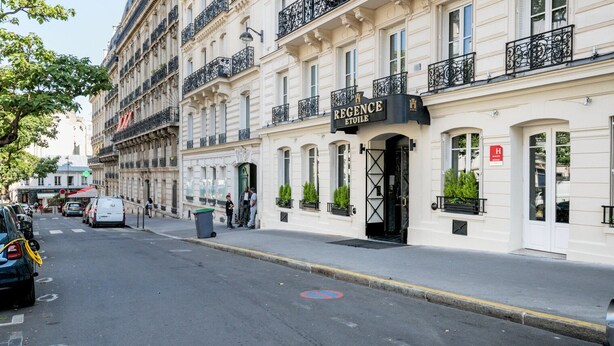 Un immeuble dont le rez-de-chaussée porte une enseigne indiquant « REGENCE ETOILE », et qui présente un style architectural classique avec des balcons et une entrée fermée par un portail.