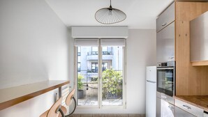 Eine kompakte Küche mit Einbauofen, einer Holzausziehtischplatte und einer Schiebeglastür zum Balkon.