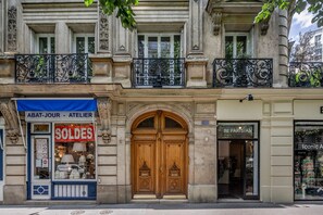 Un edificio histórico con una puerta doble de madera, un letrero que dice 'SOLDES' y una boutique llamada 'BE PARISIAN'.