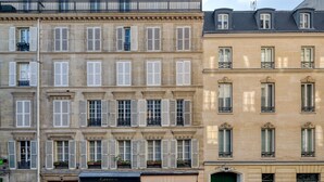 Une rangée de bâtiments de style européen classique, caractérisés par des volets uniformes et des balcons richement décorés.