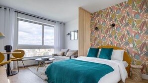 Une chambre moderne avec un grand lit, un canapé, un coin repas et une vue sur la ville.
