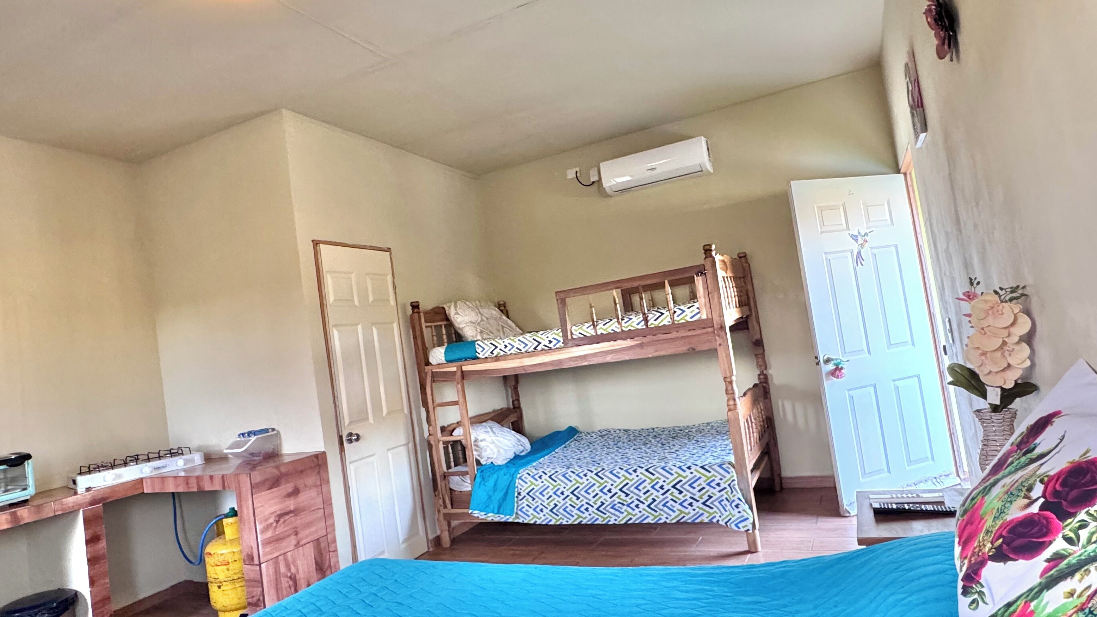 A bunk bed room with a desk, a wardrobe, and a wall-mounted air conditioner.
