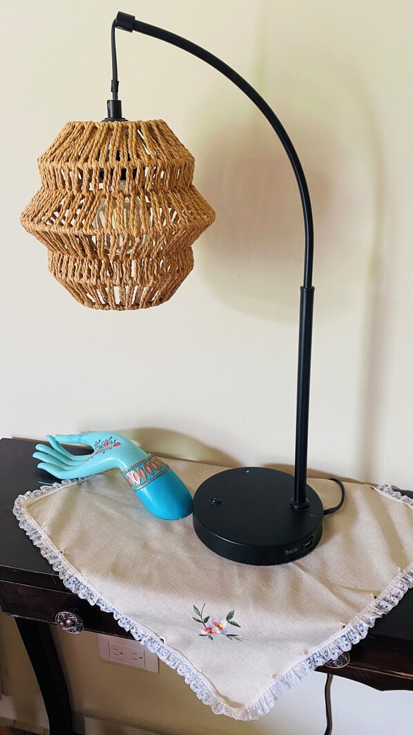 A table with a woven lamp, a blue object, and a white cloth with lace trim.
