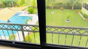Vista a través de una ventana con piscina y un patio cercado.