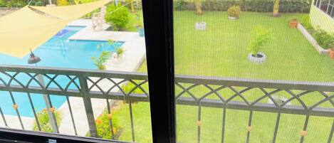 A view through a window with a pool and a fenced yard.