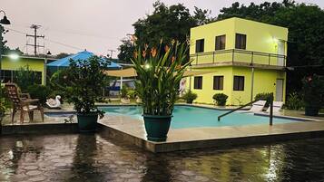 A swimming pool with a blue roof, surrounded by potted plants and a swan statue.