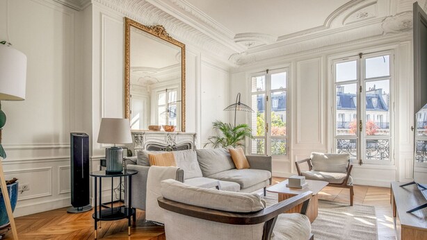 Un salon spacieux doté d’une cheminée, de sièges confortables et de grandes fenêtres offrant une vue sur la ville.