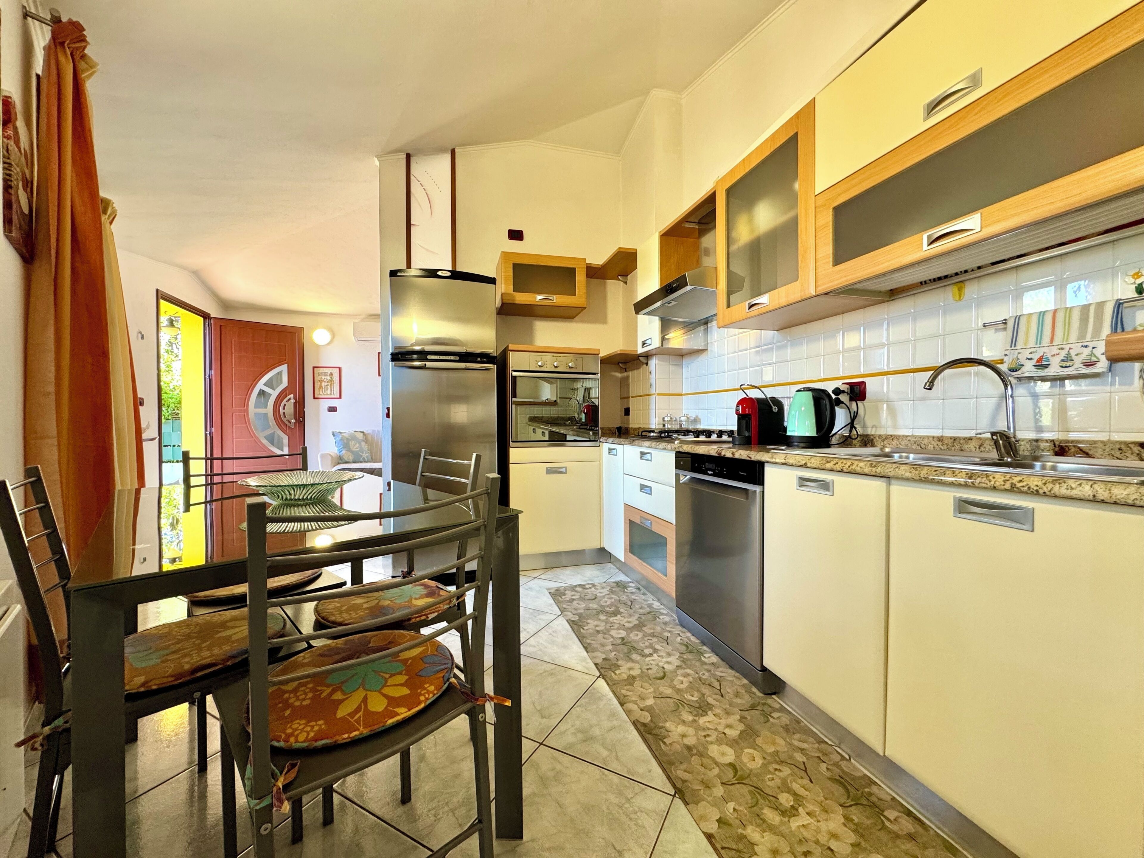 Cozinha moderna com área de refeições, eletrodomésticos de aço inoxidável e painel de azulejos.