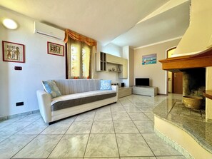 A living room with a sofa, television, fireplace, and artwork on the walls.