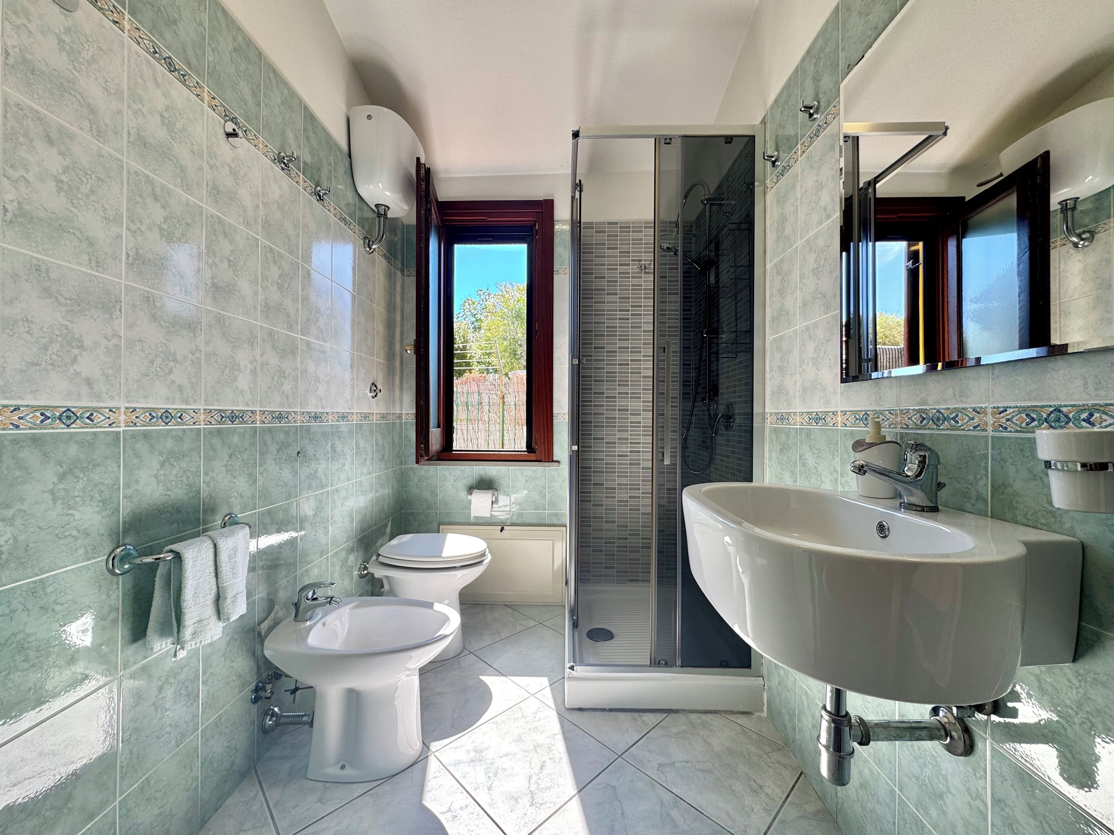 A bathroom with a shower, toilet, bidet, and sink.