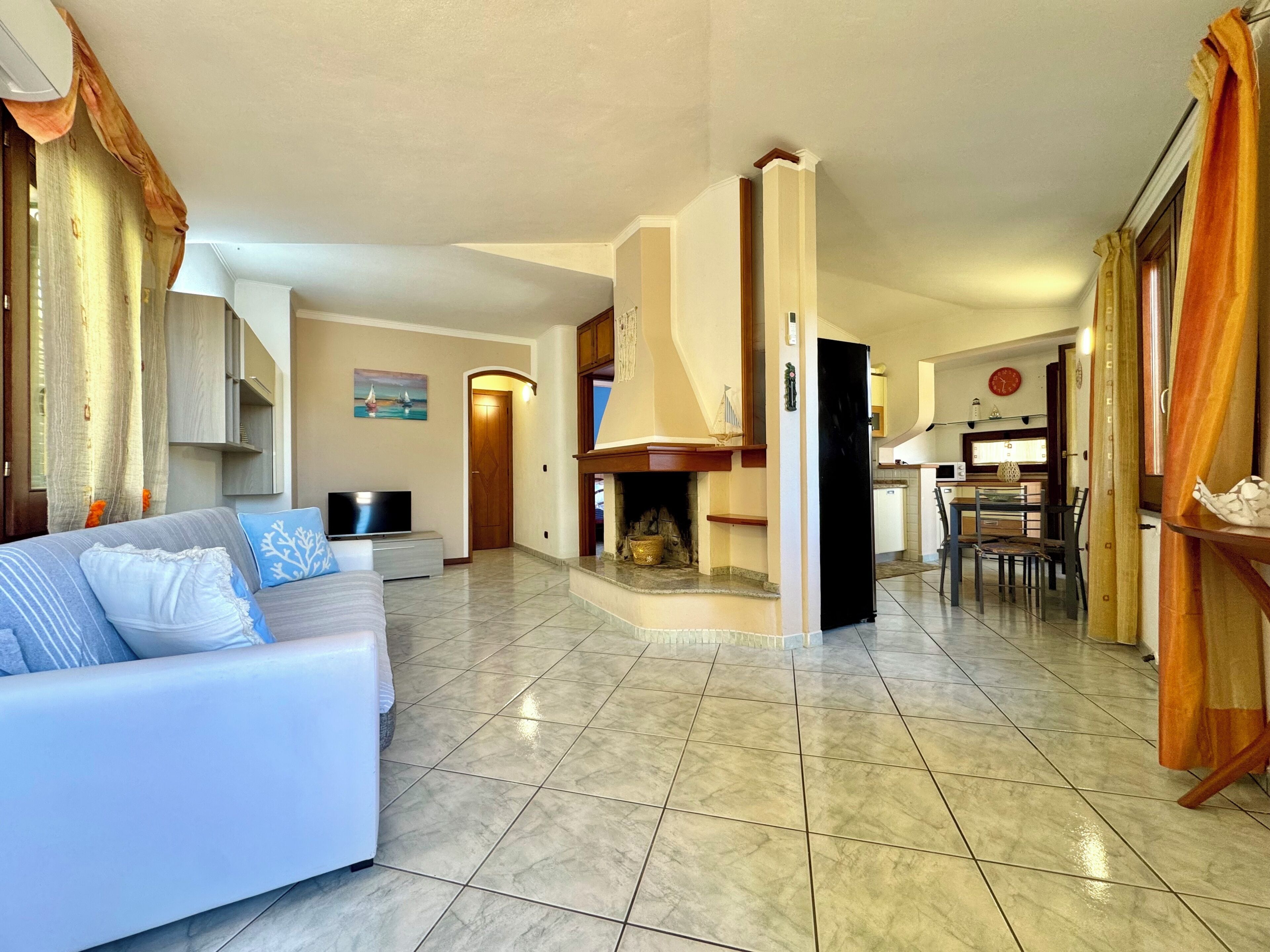 Una sala de estar con sofá, chimenea, comedor y cocina.