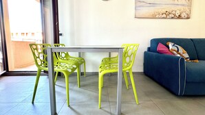 Una zona de menjador amb una taula i cadires, un rellotge a la paret i un quadre sobre el sofà.
