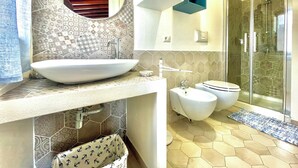 Une salle de bain moderne avec un grand lavabo ovale, des toilettes et un espace douche.