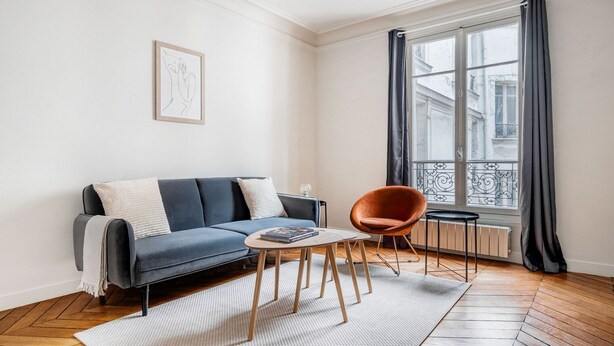 A modern living room with a sofa, a round coffee table, and a chair. - Blueground | Ternes, nr restaurants & attractions (Paris)