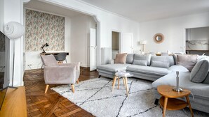 Un salon moderne avec un canapé gris, un fauteuil rose et une table basse.