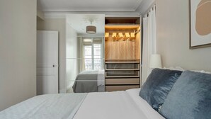 A bedroom with a bed, a wardrobe, and a window.