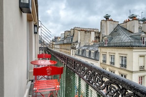 Enjoy the city view from this balcony with a metal railing and seating for two.